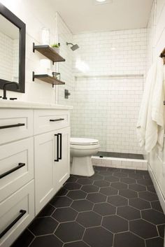 a bathroom with black and white flooring and hexagonal tiles on the walls