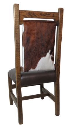 a cowhide pillow is placed on a wooden chair with leather upholstered seat