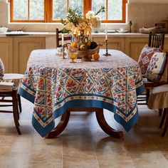 a dining room table covered with a blue and white tablecloth next to two chairs