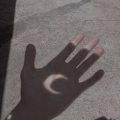 a person's hand casting a shadow on the ground