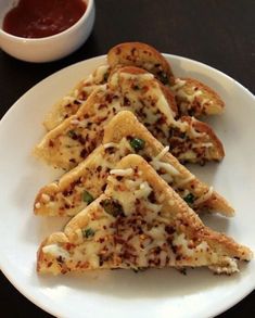 four pieces of pizza on a white plate with sauce in the bowl next to it