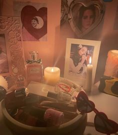 a table topped with pictures and candles next to a bowl filled with glasses on top of it