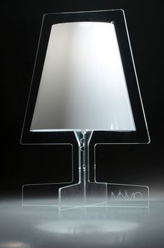 a glass lamp with a white shade on it's base and a black background