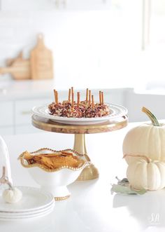 a white table topped with plates filled with food and covered in candies next to pumpkins