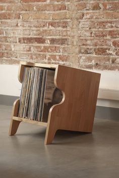 a wooden shelf with records on it in front of a brick wall