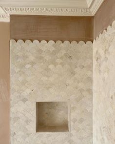 a bathroom with a white toilet sitting next to a wall covered in scallops