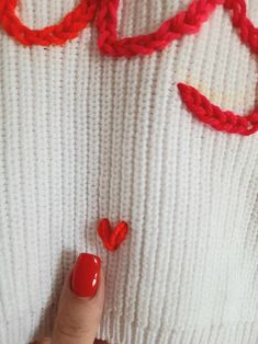 a woman's hand with red nail polish on it and some crochet