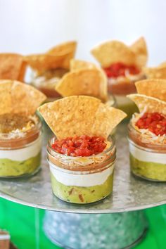 small cups filled with salsa and tortilla chips on top of a metal tray