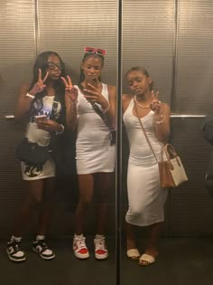 three women standing in front of a mirror making the peace sign with their hands as if they were doing something