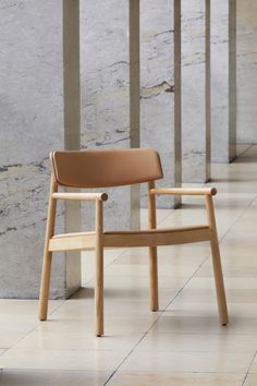 a wooden chair sitting on top of a tiled floor next to columns and pillars in front of a marble wall