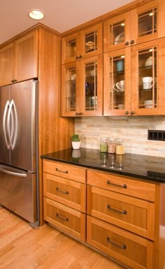 a kitchen with wooden cabinets and granite counter tops, along with stainless steel refrigerator freezer