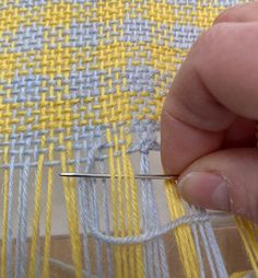 someone is stitching something yellow and white on a piece of fabric