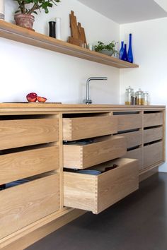 a kitchen with wooden cabinets and drawers on the counter top is filled with pots and plants