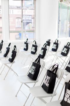 many white chairs with black bags on them