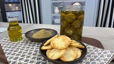 some food is sitting on a table next to a jar of pickles and olives