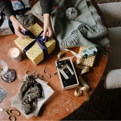 a table topped with lots of wrapping and other items next to a person's hand