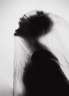 a black and white photo of a woman's head with her hair blowing in the wind