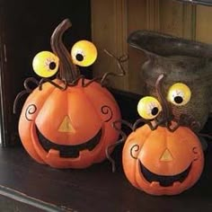 two pumpkins with googly eyes sitting on a mantle