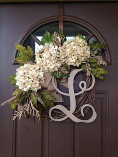 a wreath with white flowers hanging on the front door and monogrammed letter d