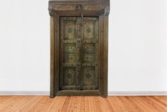 an old wooden cabinet with ornate carvings on the front and sides, against a white wall