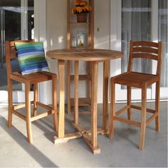 two wooden chairs sitting at a table in front of a window