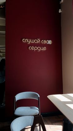 a chair sitting in front of a red wall next to a white table and chairs