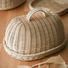 a wicker purse sitting on top of a wooden floor next to two baskets with handles