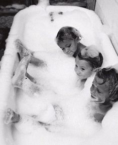 three children sitting in a bathtub with foam on it