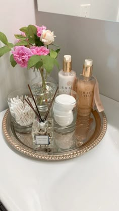 a bathroom sink with soap, lotion and flowers on the tray in front of it