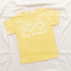 Looking for a cute tee for your kids? We have the perfect 100 Days Of School Smiley Face graphic tee addition to their closet! Also available in youth tees. Playful Summer T-shirt For School, Playful Graphic Print T-shirt For Daycare, Spring School T-shirt With Slogan, Spring Slogan T-shirt For School, Slogan T-shirt For School In Spring, Graphic Tee With Funny Print For School Year-end, Casual Yellow Tops For Birthday, Playful T-shirt For School In Spring, End Of School Year Funny Print Graphic Tee