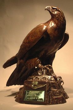 a statue of an eagle sitting on top of a wooden base with a plaque in front of it