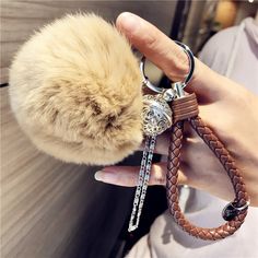 a person holding a keychain with a furry animal on it's side