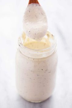 a jar filled with white sauce and a wooden spoon sticking out of it's top