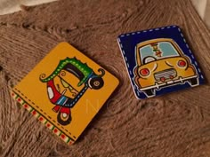 two small coasters are sitting on a brown surface with a yellow car in the background