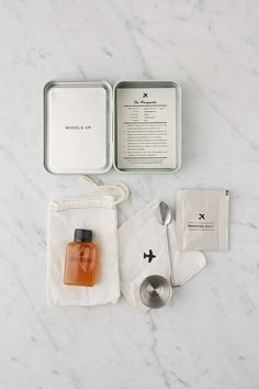 the contents of a personal care kit laid out on a marble counter top, including an empty container and spoon