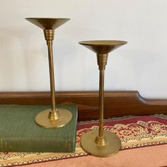 two brass candlesticks sitting on top of a rug