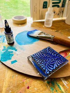 a wooden table topped with lots of paint and art supplies on top of it's surface