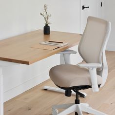 an office chair sitting next to a desk with a book on it and a plant in the corner