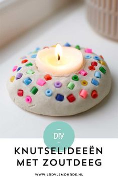 a white candle sitting on top of a cookie covered in colorful sprinkles