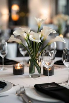 the table is set with white flowers and place settings for two people to sit at