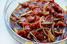 a glass bowl filled with lots of red sauce next to some sliced oranges and onions