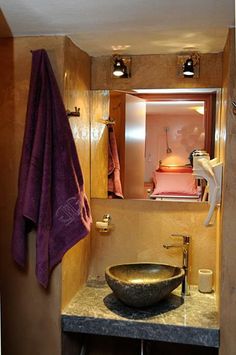 a bathroom sink sitting under a mirror next to a purple towel on top of a counter