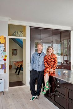 a man and woman standing next to each other in front of a kitchen counter top