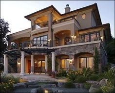 a large house with lots of windows and balconies on the second story is lit up at night