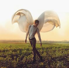 a man standing in a field with an angel wings on his back