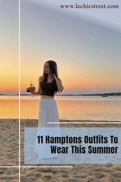 a woman standing on top of a beach next to the ocean holding a drink in her hand