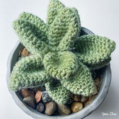 a green crocheted plant sitting in a pot filled with rocks