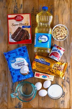 ingredients to make chocolate cake laid out on a wooden table with milk, eggs, flour, and other items