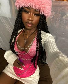 a woman wearing a pink furry hat sitting on top of a bed next to a window