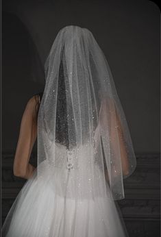 the back of a bride's wedding dress, with her veil draped over her head